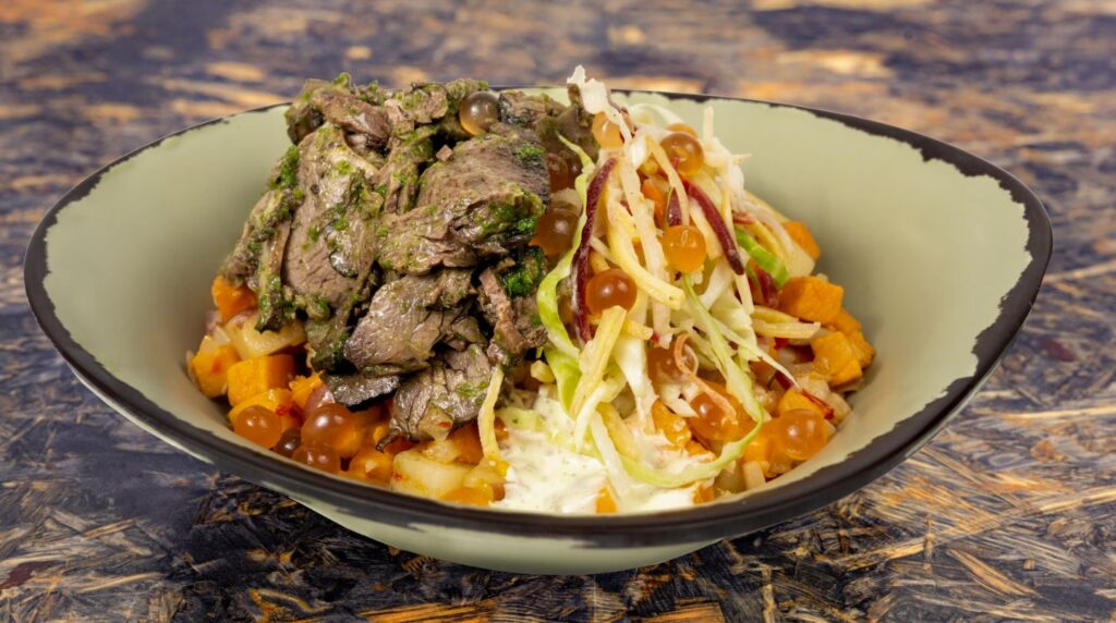 Chimichurri beef with slaw in a white bowl on a wood table